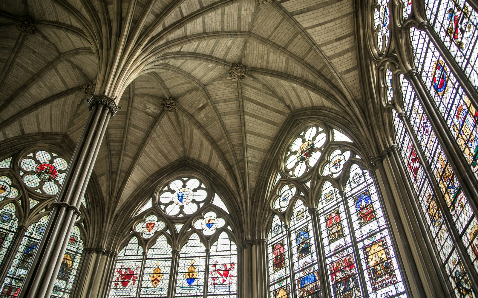 Stained glass windows and vaulted ceiling in Westminster Abbey's Chapter House, London.