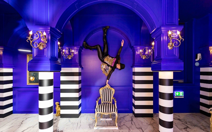 Person balancing upside down on a chair in the Royal Room, Upside Down Amsterdam.