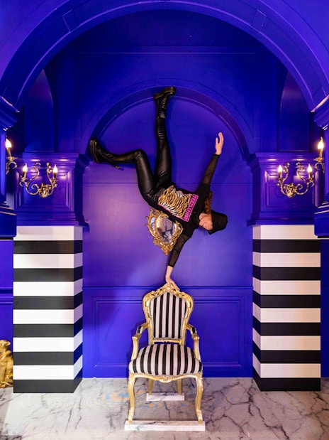 Person balancing upside down on a chair in the Royal Room, Upside Down Amsterdam.