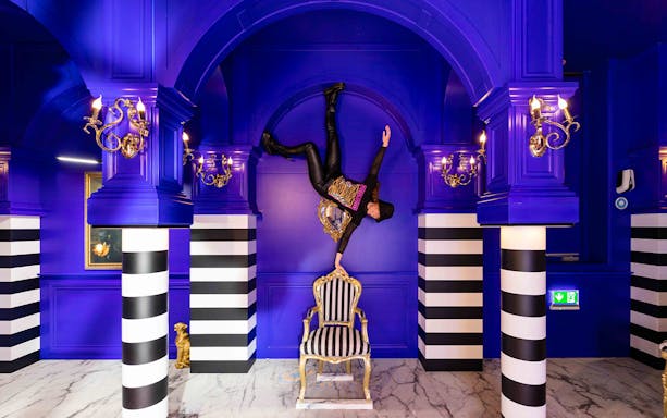 Person balancing upside down on a chair in the Royal Room, Upside Down Amsterdam.