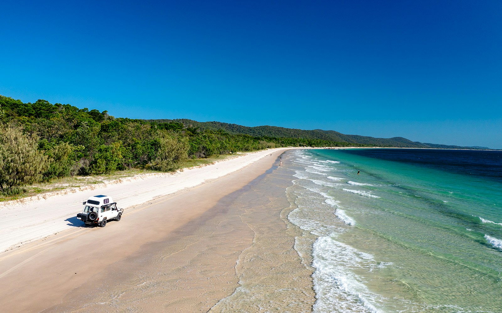 4WD vehicle driving on Moreton Island beach, highlighting offroad adventure experience.