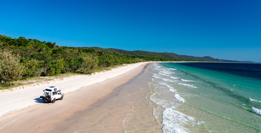 4WD vehicle driving along Moreton Island beach, highlighting offroad adventure.