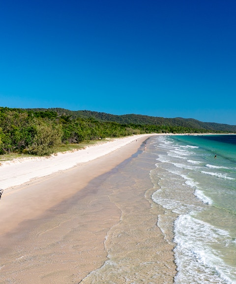 4WD vehicle driving along Moreton Island beach, highlighting offroad adventure.