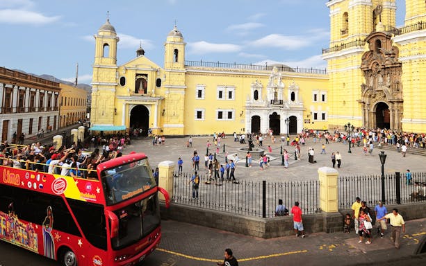 Double-decker bus on a city tour passing by historic buildings in Lima, Peru.