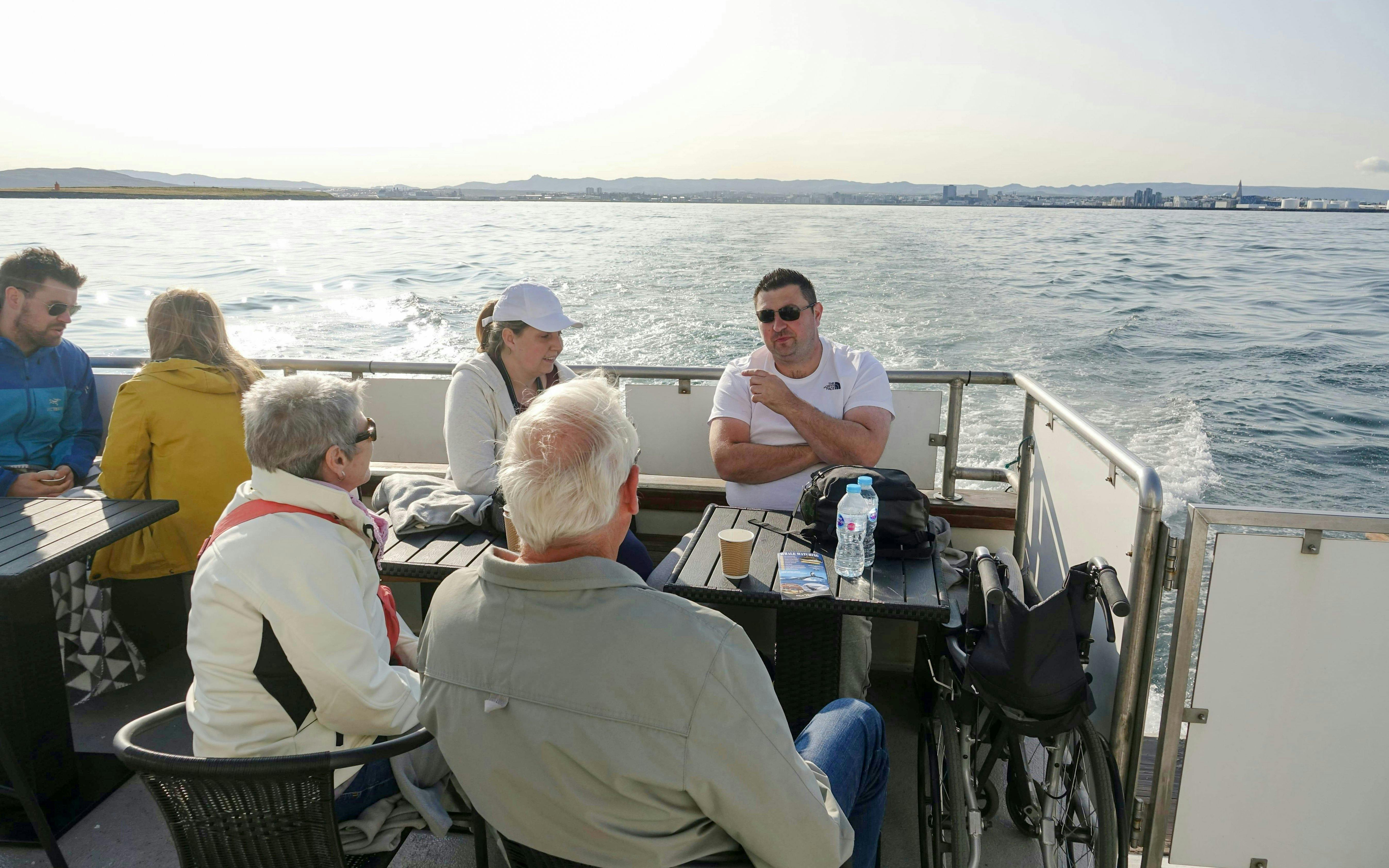Guests enjoying a conversation on the Amelia Rose yacht during a whale watching cruise in Reykjavík.