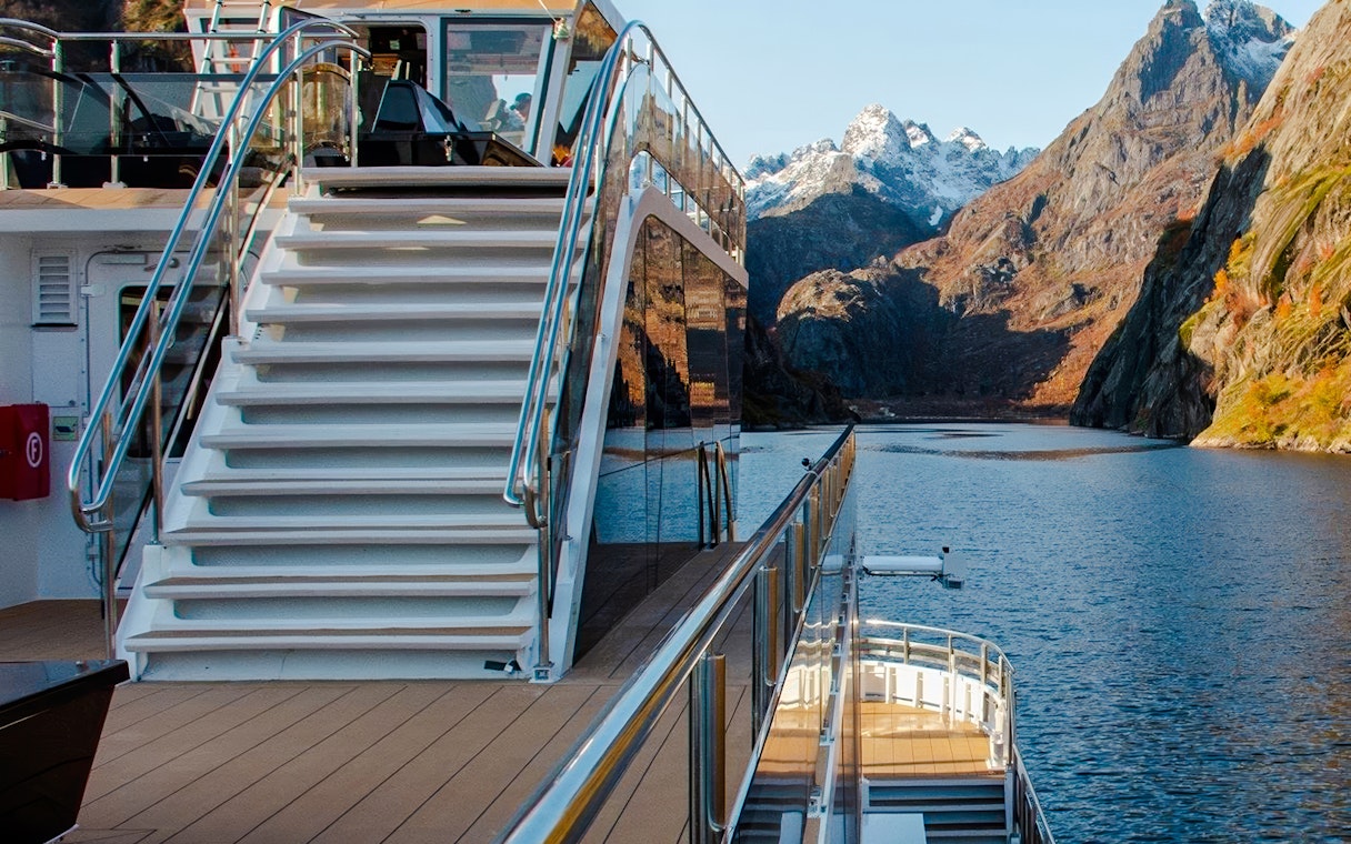 Cruise ship deck with stairs overlooking Trollfjord, Lofoten mountains in the background.