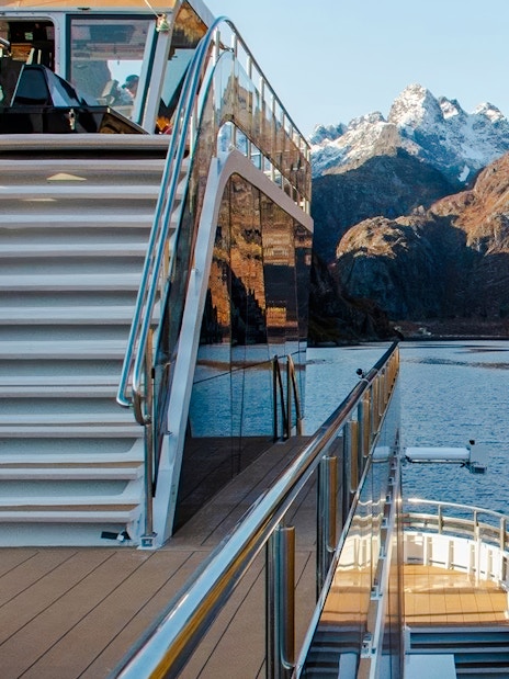 Cruise ship deck with stairs overlooking Trollfjord, Lofoten mountains in the background.