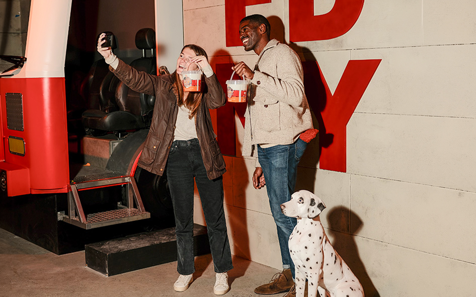 Visitors enjoying the iCandy Experience in NYC with a Dalmatian and a red bus backdrop.