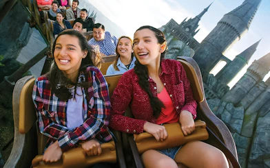 Visitors enjoying a roller coaster at Universal Studios Hollywood with Hogwarts Castle in the background.