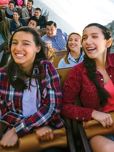 Visitors enjoying a roller coaster at Universal Studios Hollywood with Hogwarts Castle in the background.