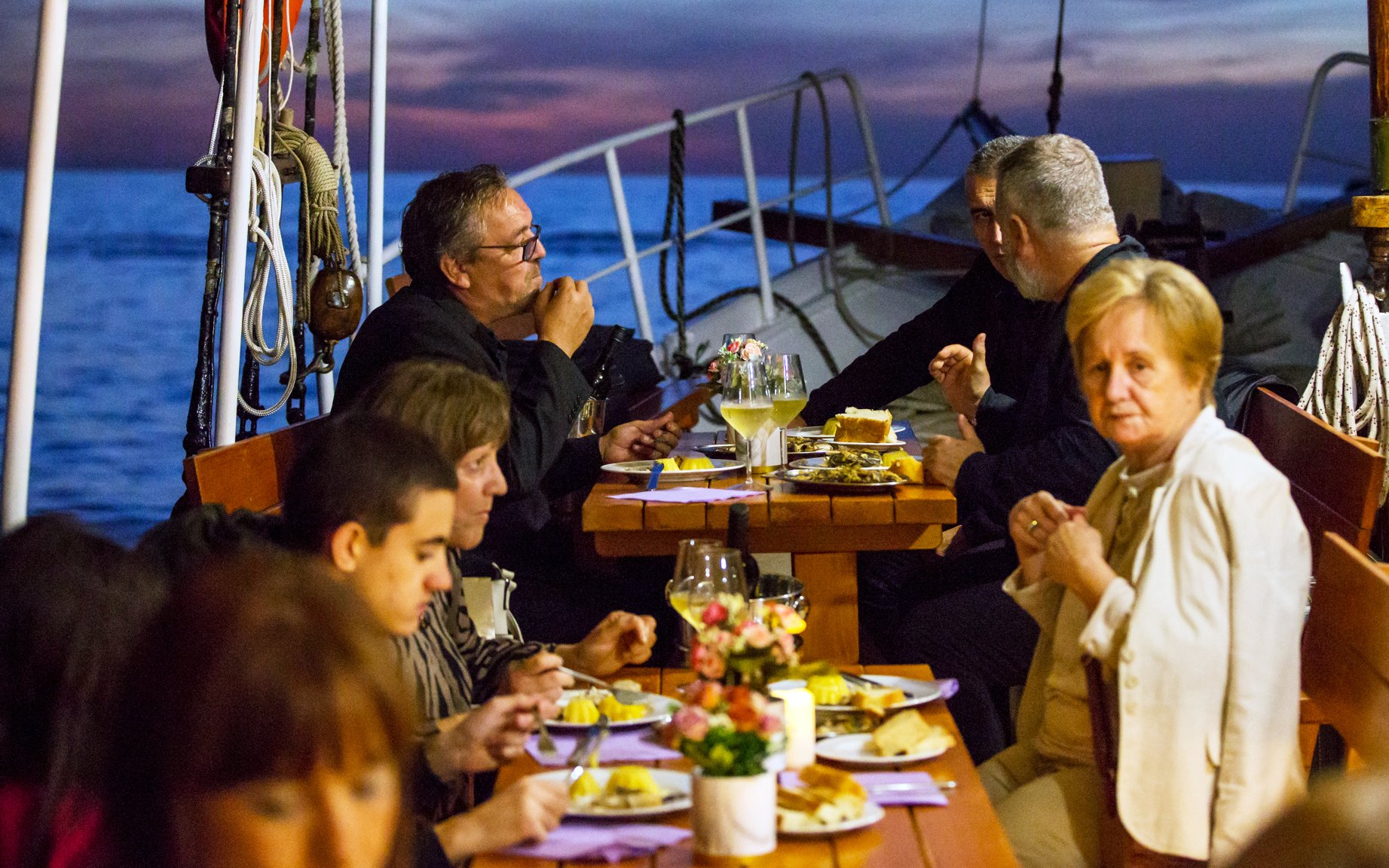 Dinner on a boat in Dubrovnik with people enjoying a meal at sunset.