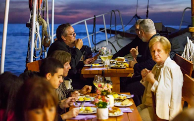 Dinner on a boat in Dubrovnik with people enjoying a meal at sunset.
