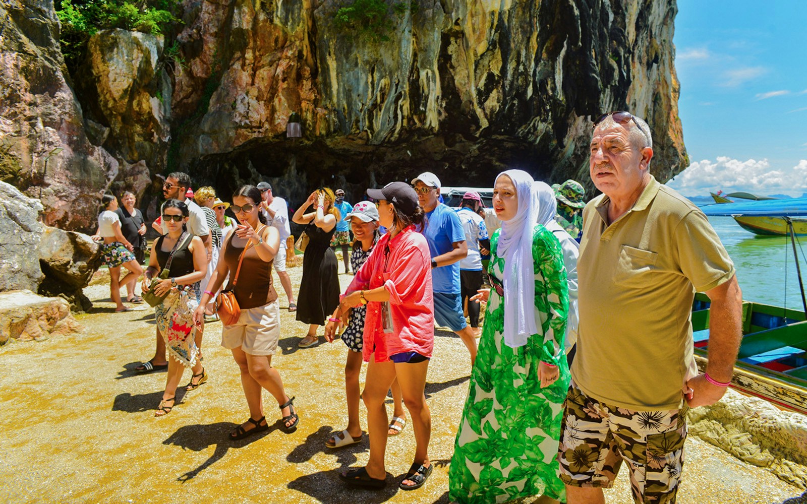 Tourists exploring rocky shoreline at James Bond Island, Phang Nga Bay.