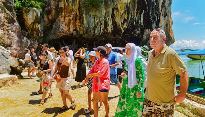Tourists exploring rocky shoreline at James Bond Island, Phang Nga Bay.