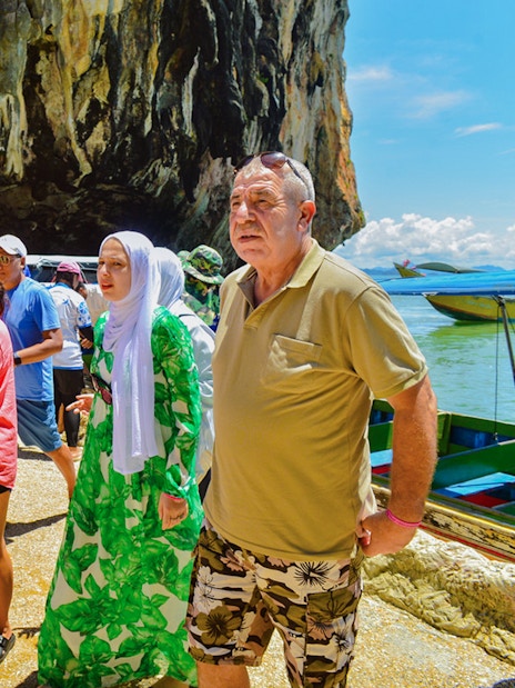 Tourists exploring rocky shoreline at James Bond Island, Phang Nga Bay.
