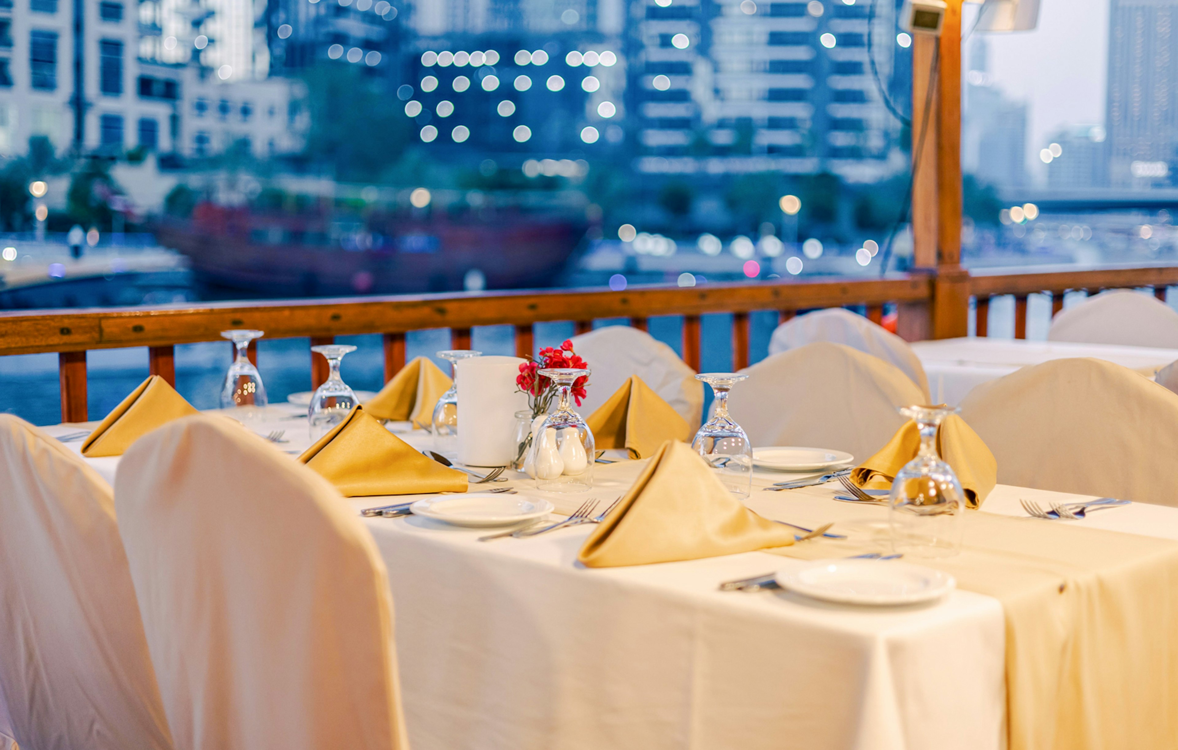 Dining setup on a dhow cruise with city skyline in the background.