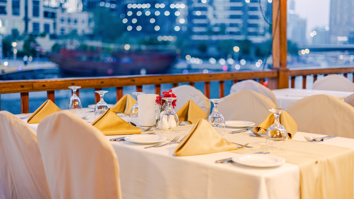 Dining setup on a dhow cruise with city skyline in the background.