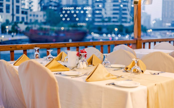 Dining setup on a dhow cruise with city skyline in the background.