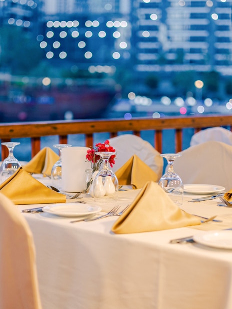 Dining setup on a dhow cruise with city skyline in the background.