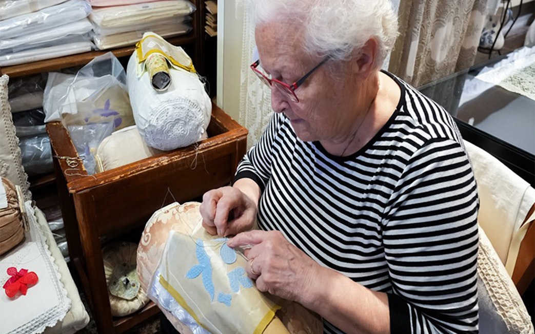 Elderly woman crafting lace at Burano lace school.