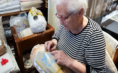 Elderly woman crafting lace at Burano lace school.