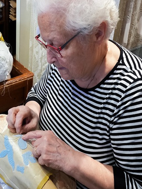 Elderly woman crafting lace at Burano lace school.