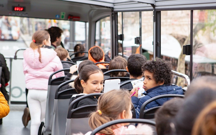 Children enjoying a Tootbus tour in Paris, looking at maps and tablets.