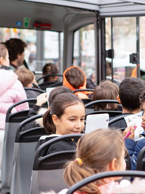 Children enjoying a Tootbus tour in Paris, looking at maps and tablets.