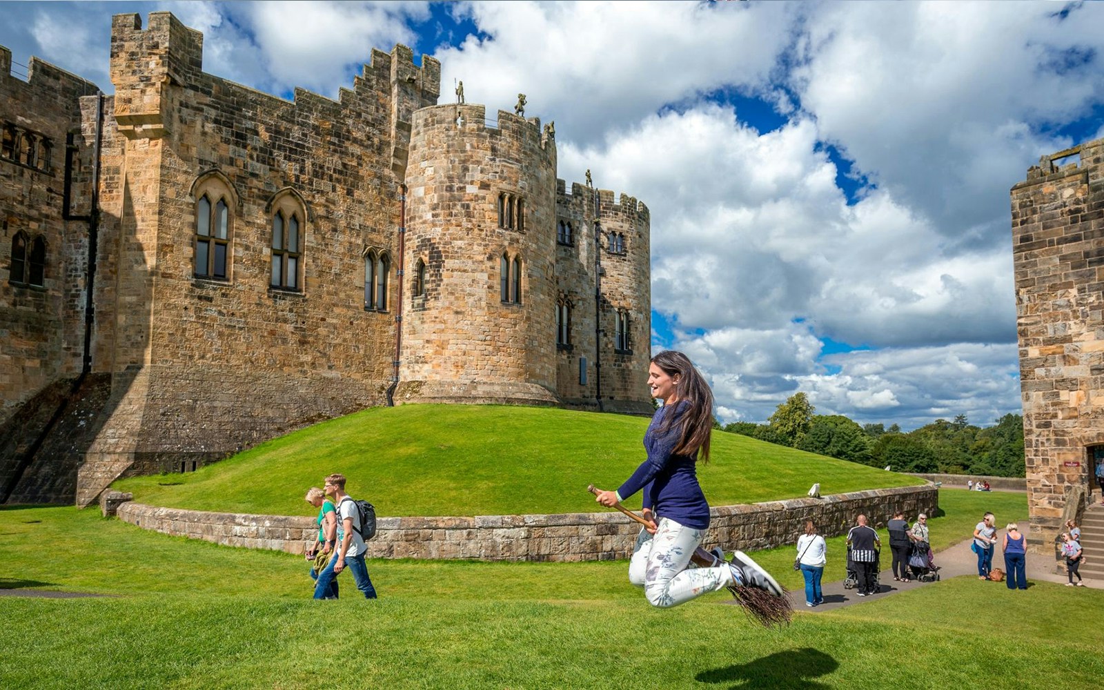 Alnwick Castle courtyard with visitors, known for Harry Potter filming, part of Edinburgh day tour.