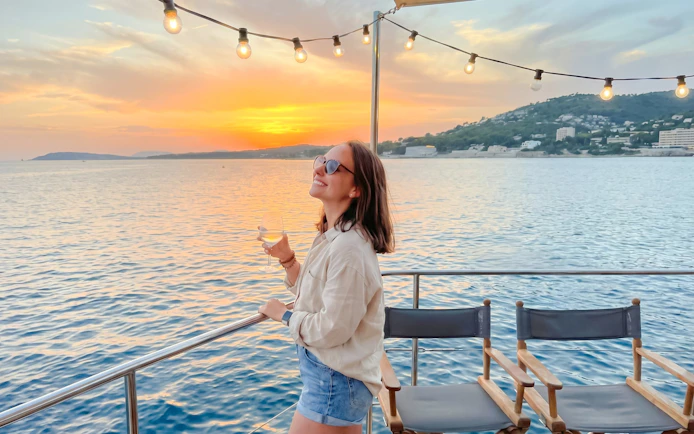 Sunset catamaran cruise with apéritif, woman enjoying ocean view.