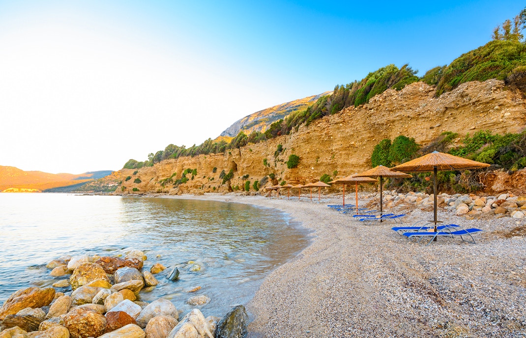 Votsalakia Beach shoreline with sunbathers and clear blue waters, Samos Island, Greece.