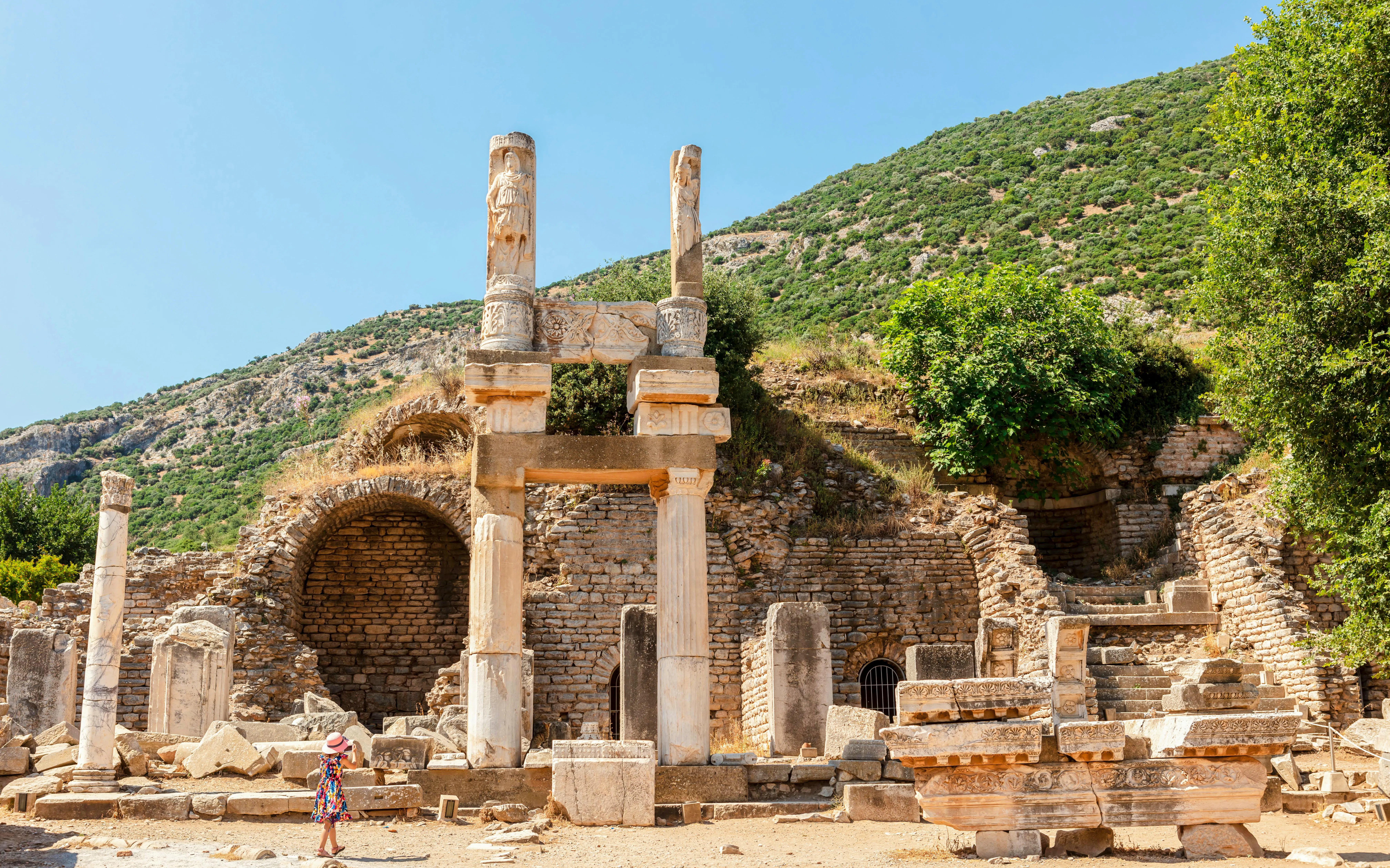 Temple of Domitian ruins at Ephesus archaeological site, Turkey, with visitor exploring.