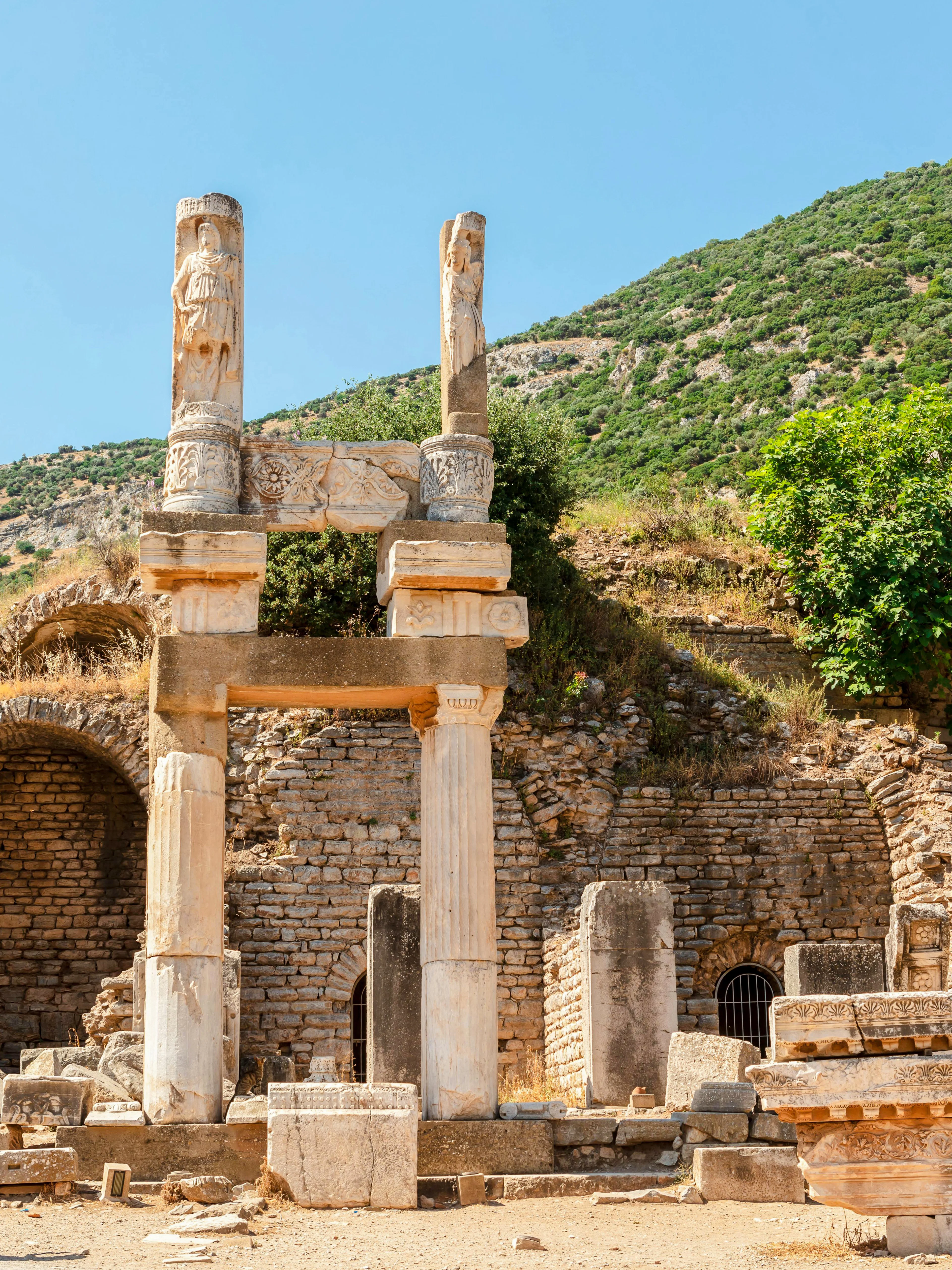 Temple of Domitian ruins at Ephesus archaeological site, Turkey, with visitor exploring.