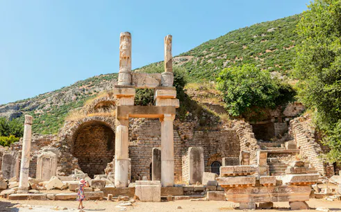 Temple of Domitian ruins at Ephesus archaeological site, Turkey, with visitor exploring.