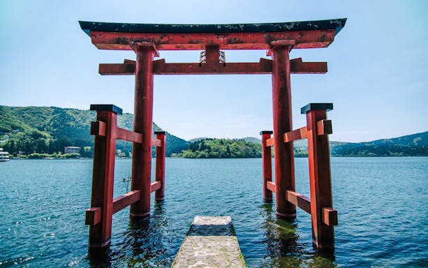 Torii gate at Lake Ashi with mountains in the background, Japan.