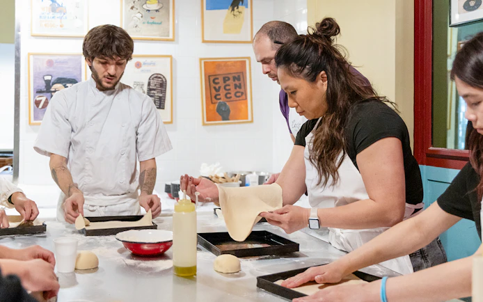Participants making pizza dough in a Rome kitchen cooking class.