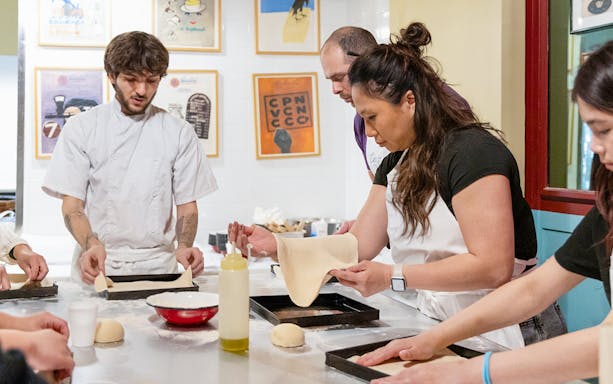Participants making pizza dough in a Rome kitchen cooking class.