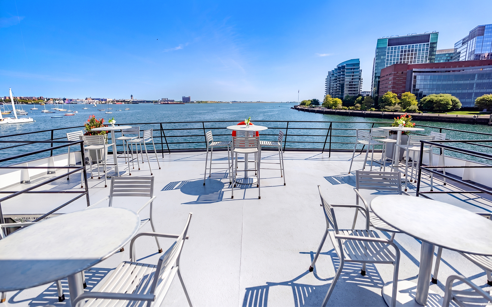 Outdoor dining area on a Boston Premier Lunch Cruise ship with harbor views.