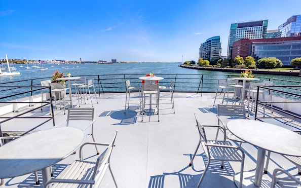 Outdoor dining area on a Boston Premier Lunch Cruise ship with harbor views.