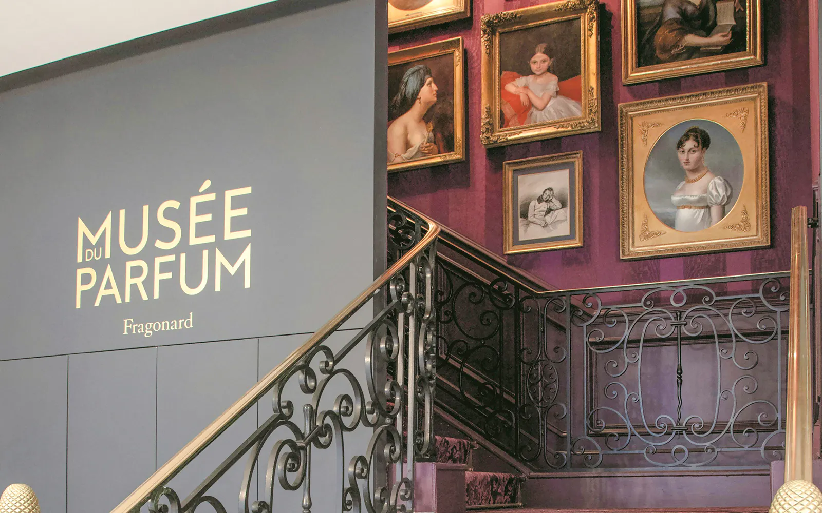 Musée du Parfum Fragonard entrance with framed portraits on a staircase wall.