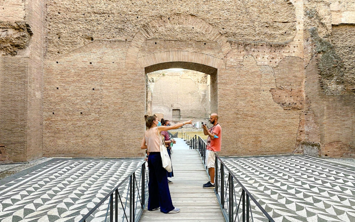 Visitors exploring the ancient ruins of the Baths of Caracalla in Rome.