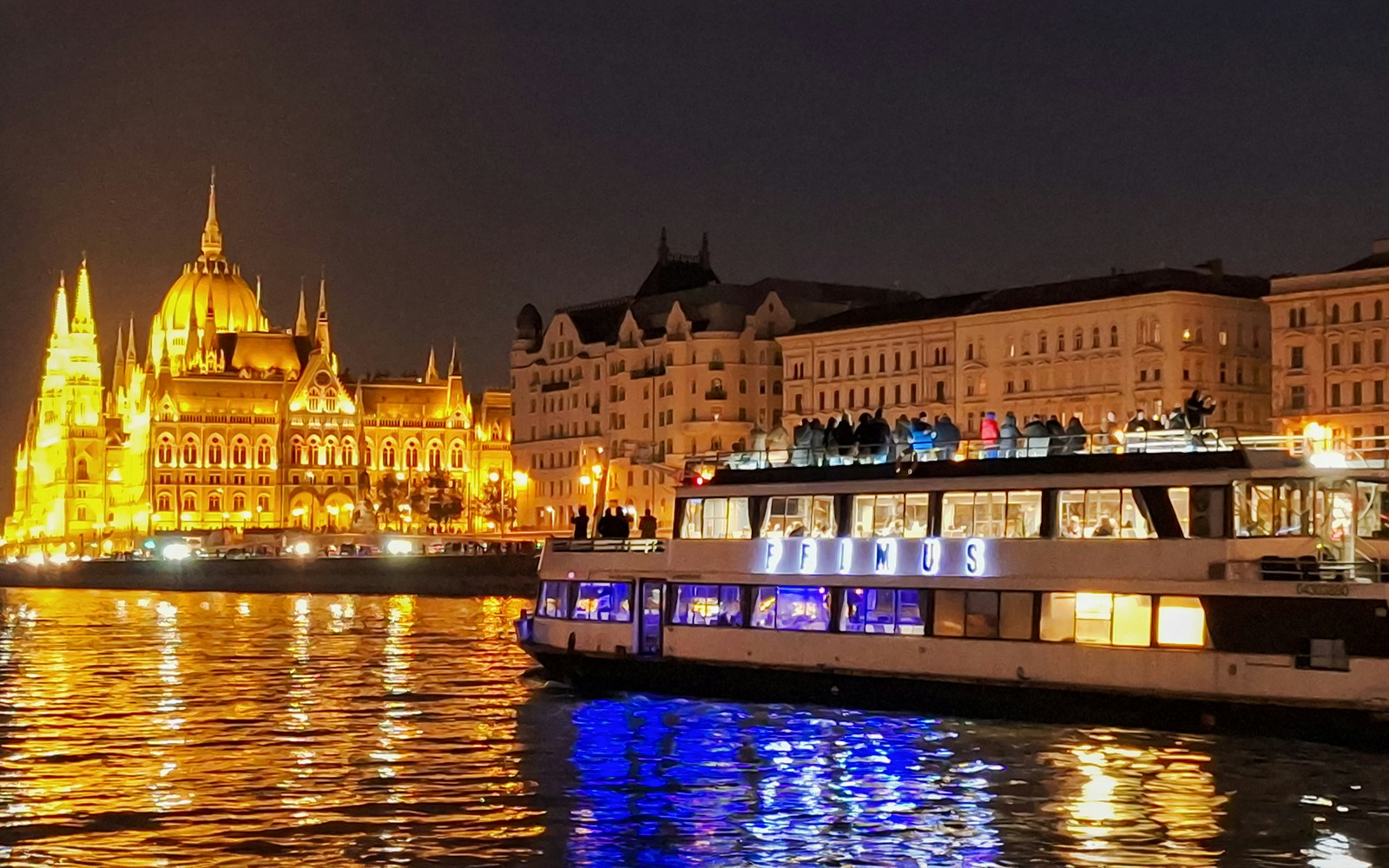 Evening view of Budapest Parliament from Danube River during dinner cruise.