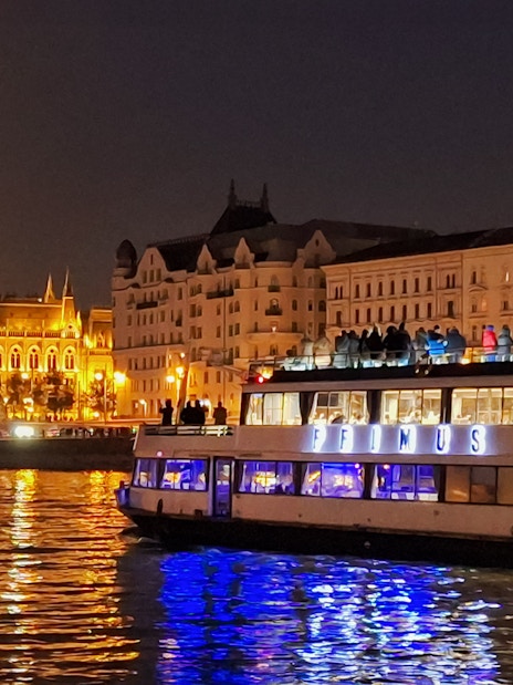 Dinner cruise on the Danube River with Budapest Parliament illuminated at night.