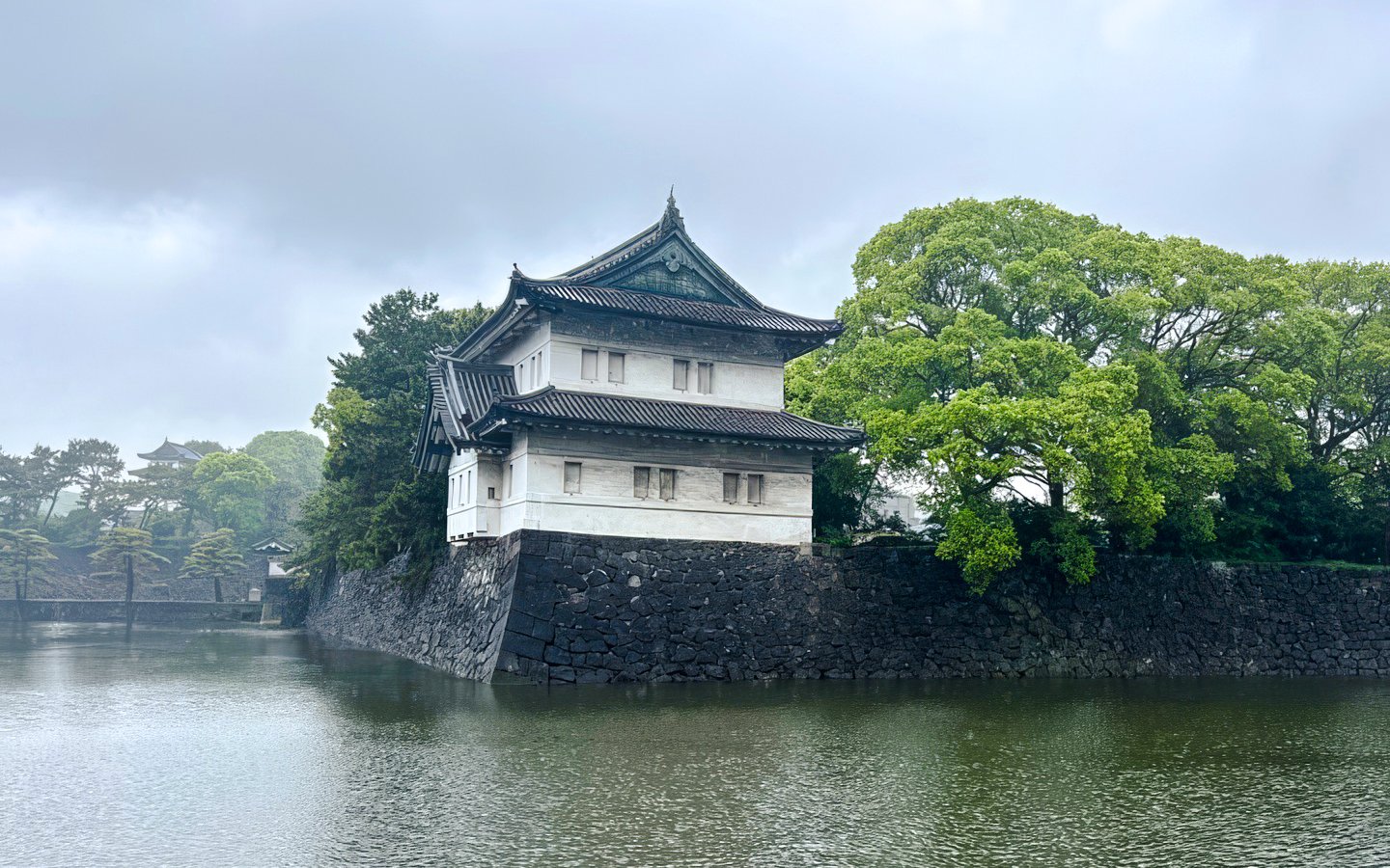 Imperial Palace guardhouse by the moat in Tokyo, surrounded by lush greenery.