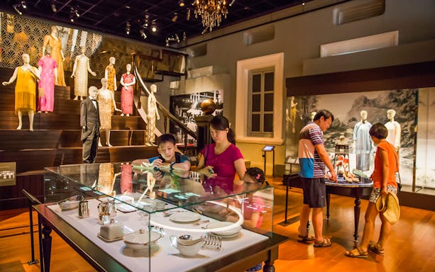Visitors exploring exhibits at the National Museum of Singapore, featuring historical fashion displays.