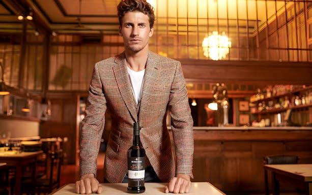 Man standing in Burmester Cellars with a bottle of Tordiz wine on the table.