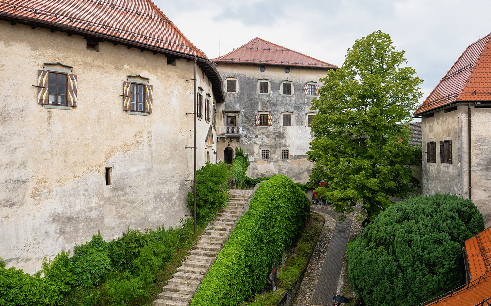 Inner courtyard of Bled Castle in Slovenia with stone path and greenery.