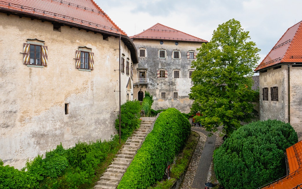 Inner courtyard of Bled Castle in Slovenia with stone path and greenery.