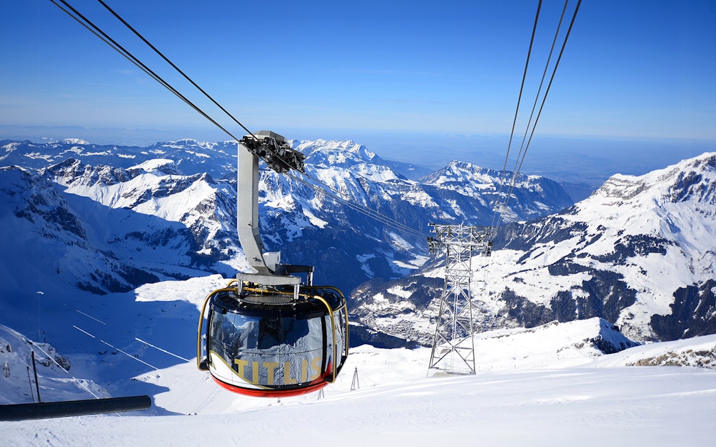 Titlis Rotair cablecar ascending over snowy Swiss Alps.