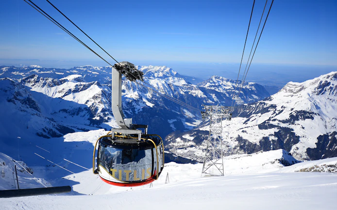 Titlis Rotair cablecar ascending over snowy Swiss Alps.